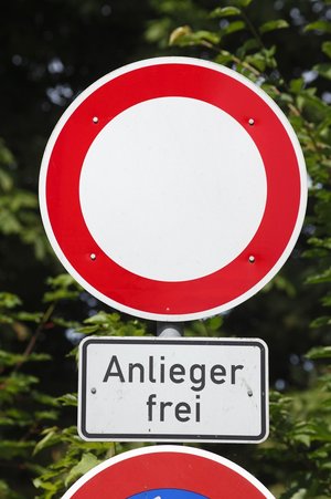 Verkehrszeichen 'Durchfahrt verboten' (rotes rundes Schild mit weißer Mitte) mit Zusatzschild 'Anlieger frei' (weißes rechteckiges Schild mit schwarzer Schrift). Bedeutet: Allgemeines Fahrverbot, aber Anlieger mit berechtigtem Anliegen dürfen passieren.