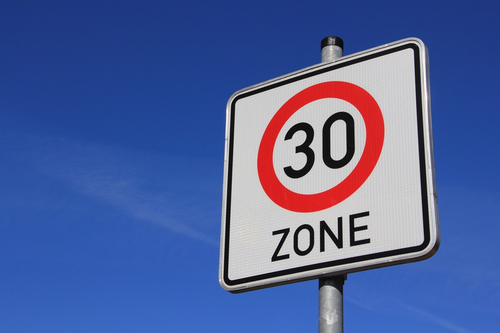 Verkehrsschild für Tempo-30-Zone vor blauem Himmel. Schwarze 30 in einem roten Kreis