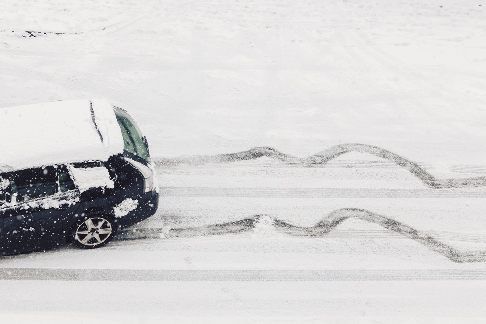 Ein Auto rutscht im Winter gefährlich eine rutschige, mit Eis und Schnee bedeckte Straße hinunter